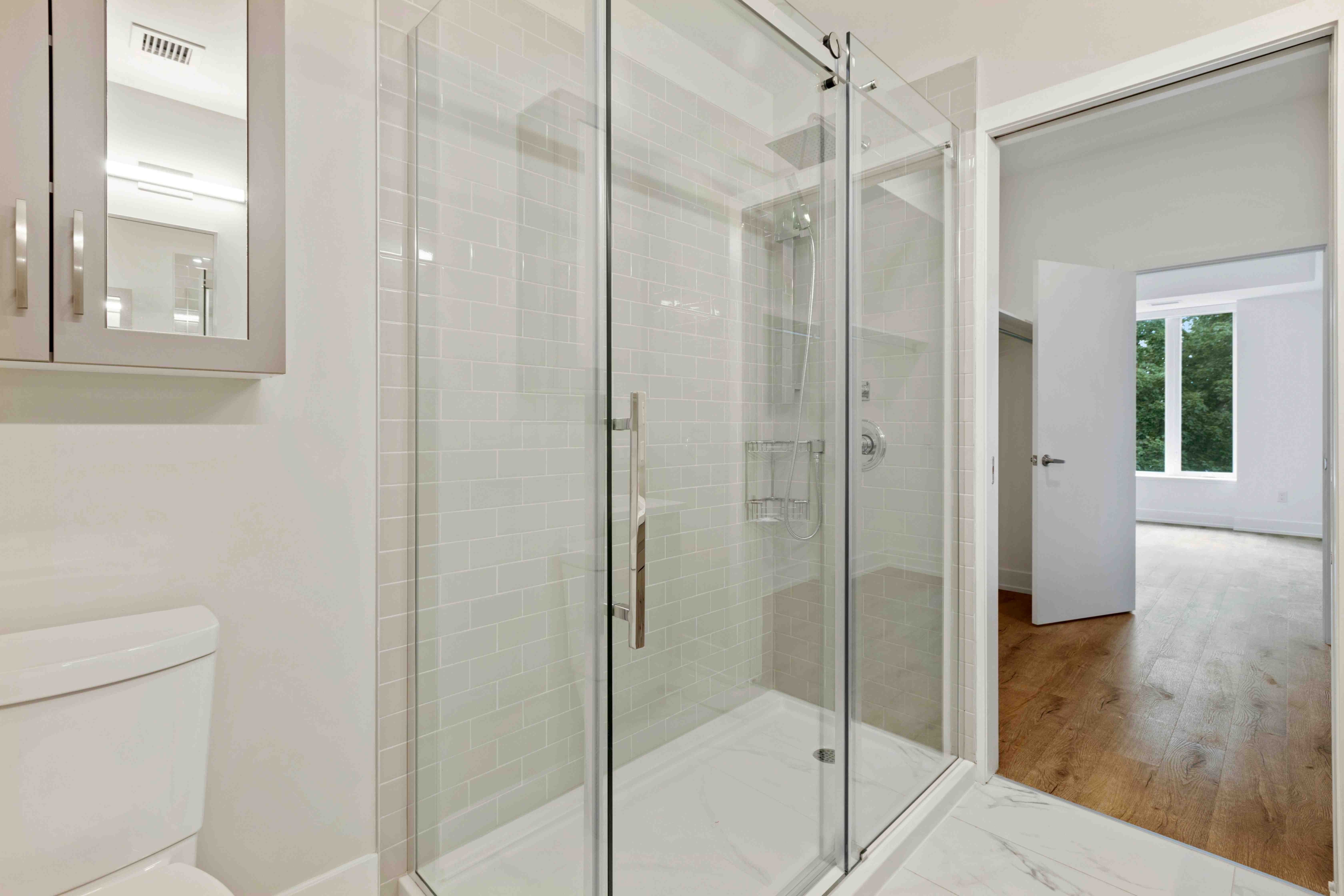 Panneau de verre transparent sur mesure parfaitement ajusté dans une structure de douche contemporaine.